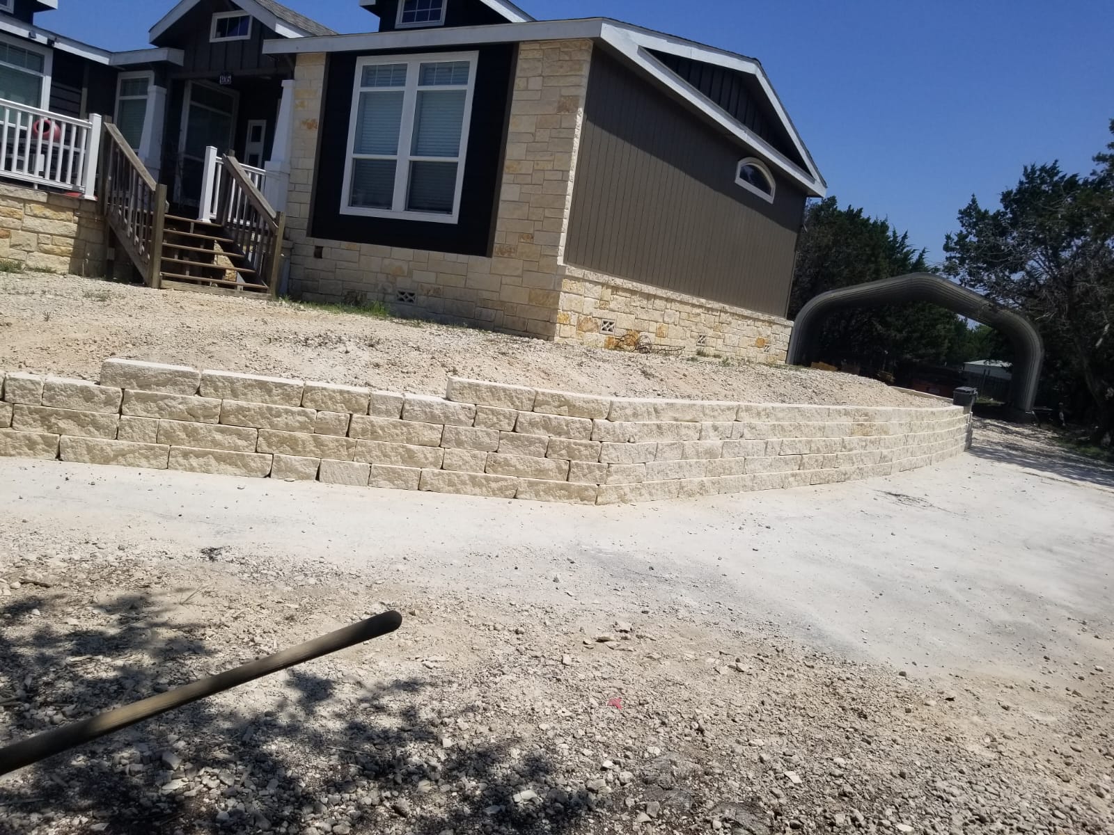 Curved light-colored retaining wall at a sloped front yard
