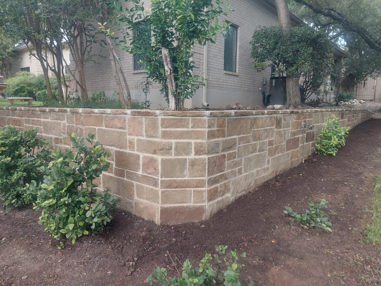Stone-faced retaining wall installed around a landscaped side yard