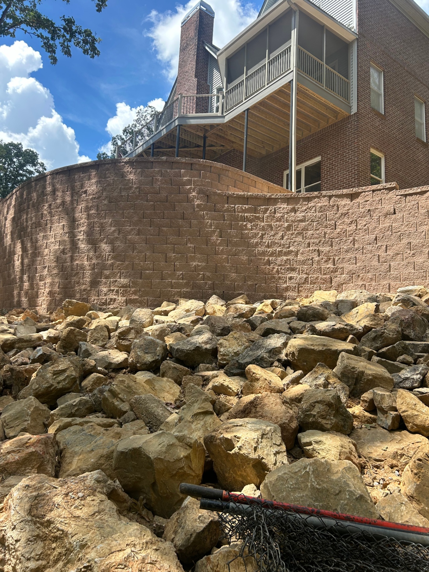 Large curved retaining wall with natural stone riprap below a raised deck