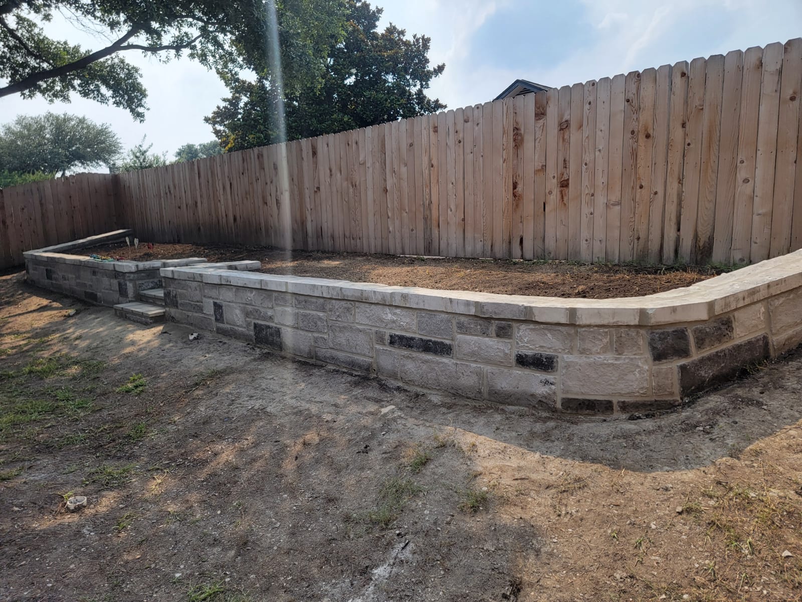 Terraced retaining wall with integrated steps and capstone finish
